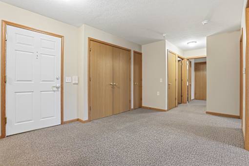 A hallway with white doors and carpeted floors.
