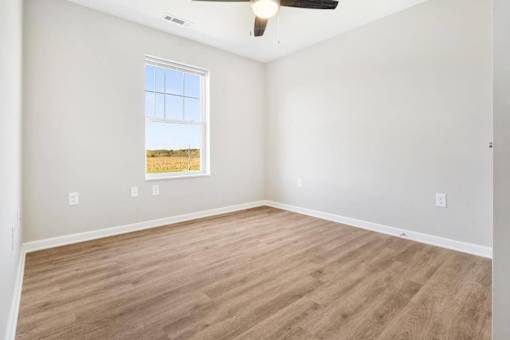an empty living room with wood floors and a window