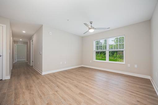 A room with a ceiling fan and a window overlooking a green area.