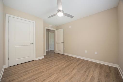 A room with a ceiling fan and wooden flooring.