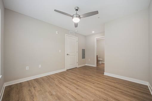 A room with a ceiling fan and wooden flooring.