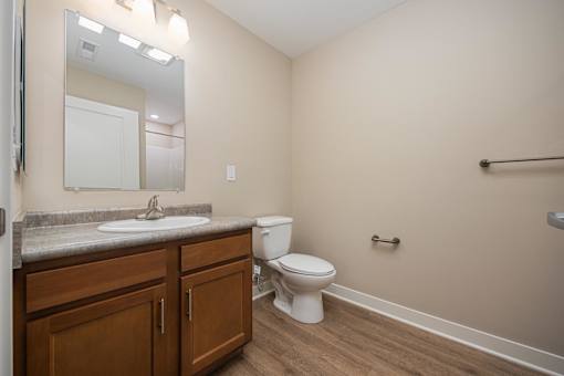 A bathroom with a toilet, sink, and mirror.