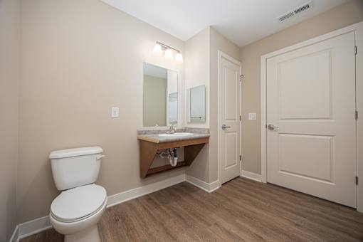 A bathroom with a toilet, sink, and mirror.