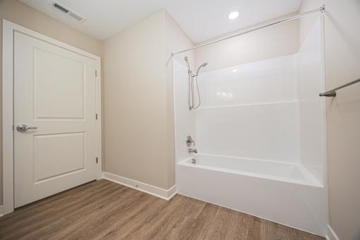 A white bathroom with a door and a bathtub.