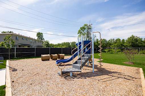 A playground with a blue slide and a brown gravel ground.