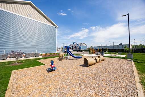 A playground with a slide and a play area with a wooden structure.