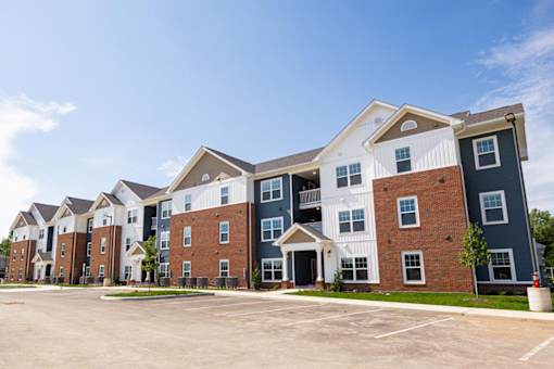 A large apartment complex with multiple buildings and parking spaces in front.