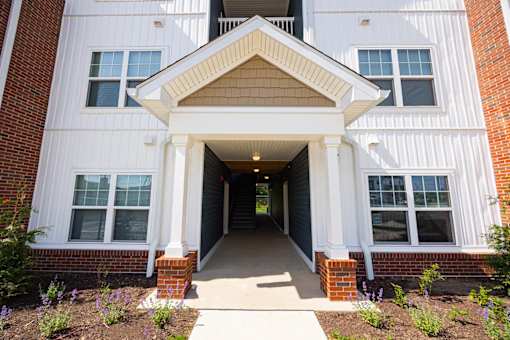 A white building with a covered walkway leading to the front door.
