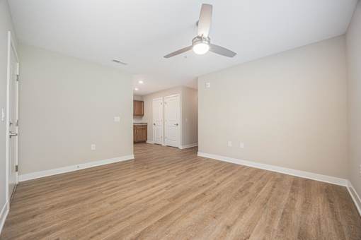 A room with a ceiling fan and wooden flooring.