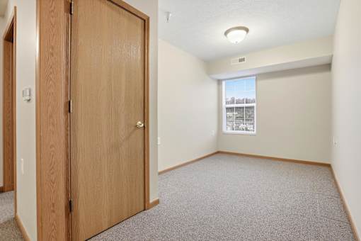 A room with a wooden door and carpeted floor.