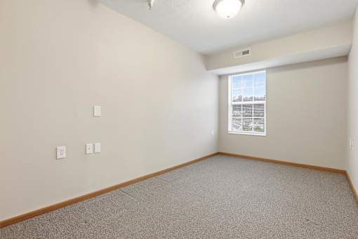 A room with a window and a carpeted floor.