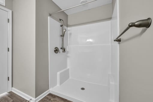 A white shower stall with a glass door and a shower head.