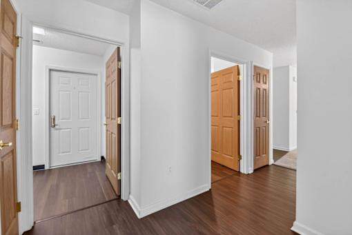A hallway with white walls and wood floors with two doors on either side.