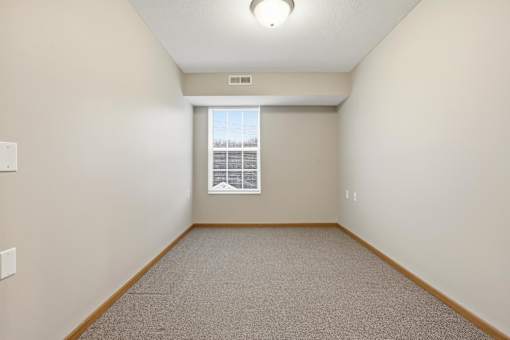 A room with a window and carpeted floor.