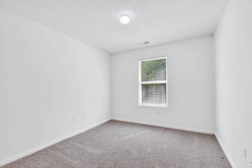 A room with a window and carpeted floor.
