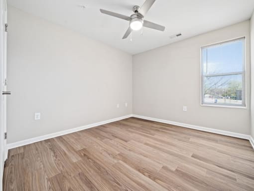 an empty living room with a ceiling fan and a window