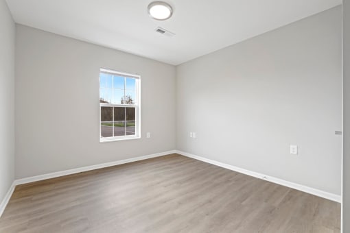 an empty living room with wood floors and a window