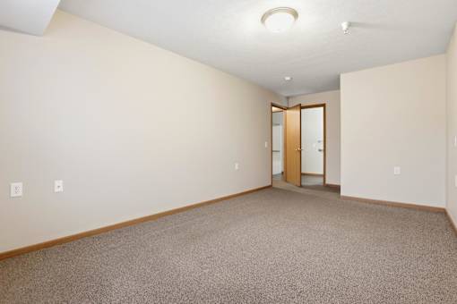 A room with a carpeted floor and a wooden door.