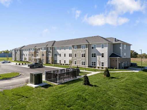 an exterior view of an apartment building with a parking lot