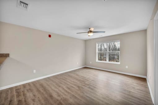 an empty living room with a ceiling fan and a window
