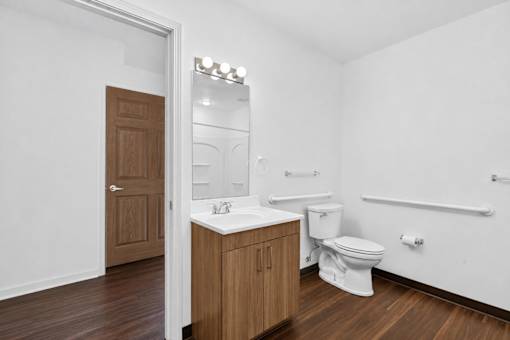 A white bathroom with a toilet, sink, and mirror.