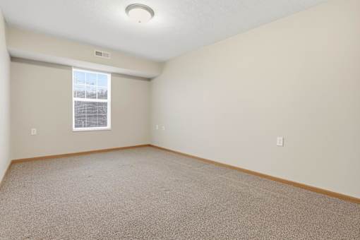 A room with a window and carpeted floor.