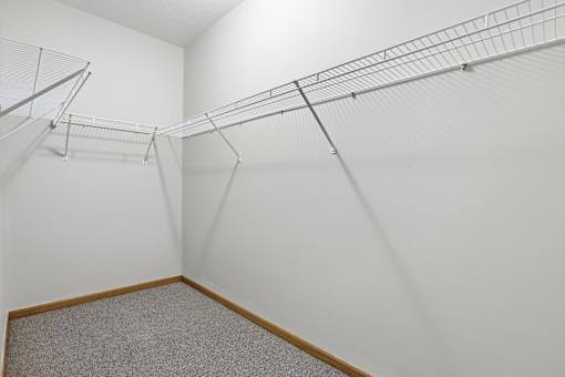 Empty room with a grey carpet and a white wall.