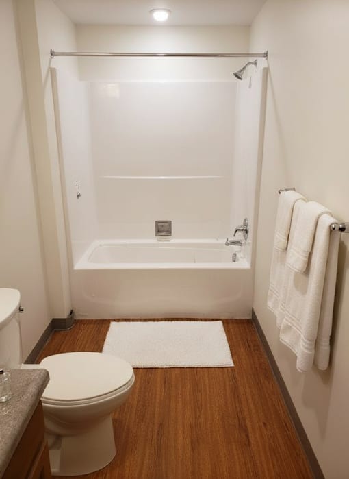 A white toilet sits next to a white bathtub in a small bathroom.