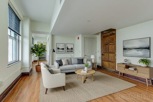 A living room with a grey couch, a coffee table, and a large painting on the wall.