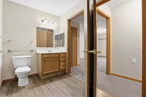 A bathroom with a toilet, sink, and mirror.