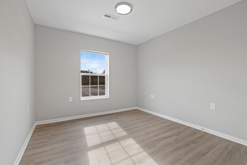 an empty living room with wood floors and a window