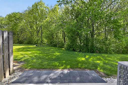 A backyard with a wooden fence and a paved walkway.