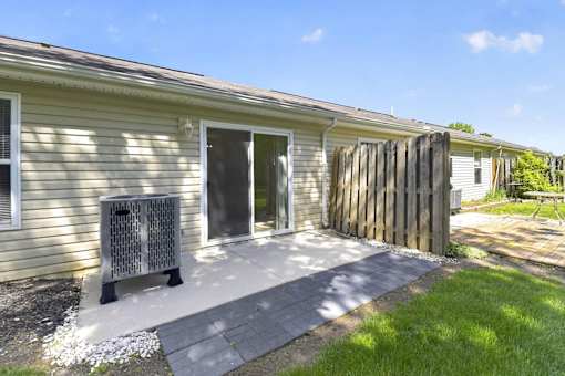 A house with a grey door and a grey bench in front of it.