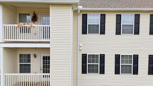 A white house with a balcony and black shutters.