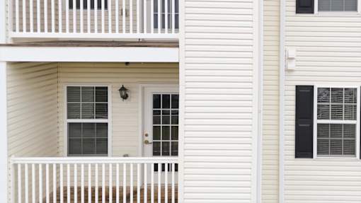 A white house with a balcony and a door.