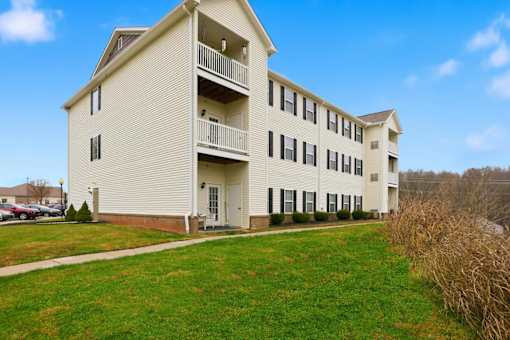 A large white apartment building with a balcony on the second floor.
