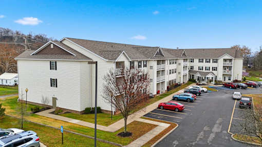 A parking lot in front of a white building with a blue sky in the background.