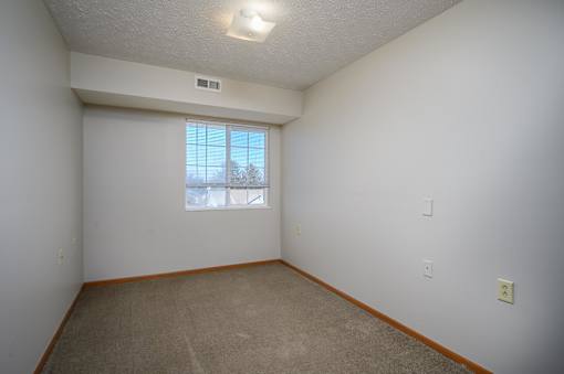 A room with a window and a carpeted floor.