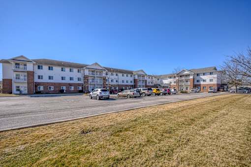 A row of apartment buildings with cars parked in front.