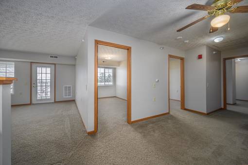 A spacious room with a ceiling fan and carpeted floor.