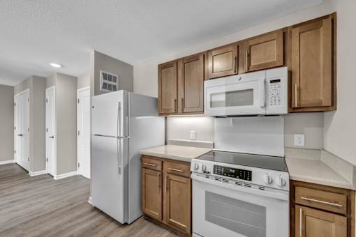 A kitchen with white appliances and wooden cabinets.