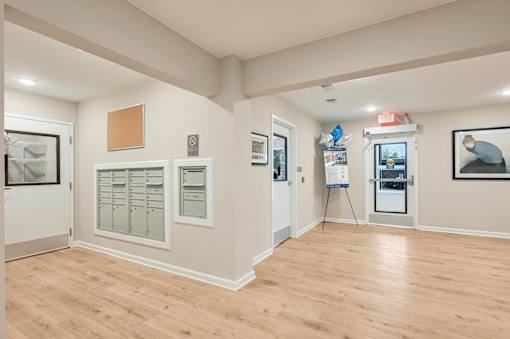 A room with a wooden floor and white walls, with a framed picture on the right wall.