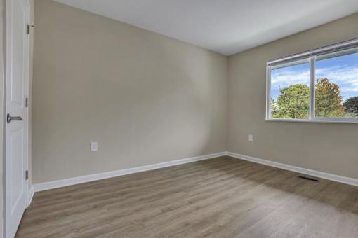 A room with a window showing trees and sky outside.