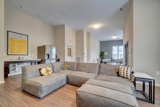 a large couch in a living room with a kitchen in the background