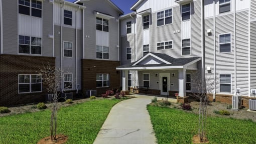 a pathway leading to an apartment building with a porch
