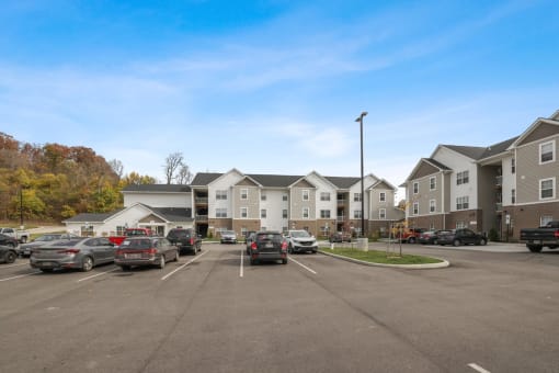 a parking lot with cars in front of an apartment complex
