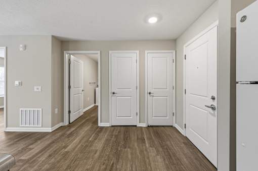 A hallway with white doors and wooden floors.
