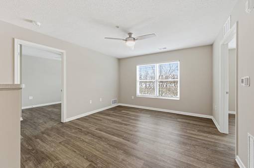 A room with a ceiling fan and a window with blinds.