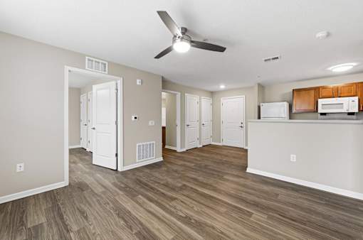 A room with a ceiling fan and wooden flooring.
