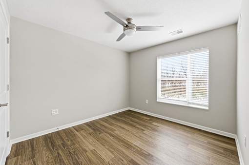 A room with a ceiling fan and a window with blinds.